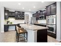 Modern kitchen featuring dark wood cabinets, granite countertops, and stainless steel appliances at 119 Ortega Ct, Erie, CO 80516