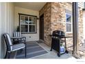 Cozy patio with stone accents, featuring a grill, table, and chairs for relaxing outdoor living at 1481 Harebell St, Berthoud, CO 80513