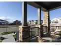 Covered front porch featuring stone pillars, comfortable seating, and a view of the street at 1592 Ash Dr, Erie, CO 80516