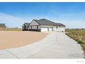 Rear exterior featuring a three-car garage, concrete driveway, white siding, and black trimmed windows at 16474 Essex S Rd, Platteville, CO 80651