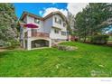 Spacious backyard with a covered patio, a deck with an umbrella, and plenty of green space for outdoor activities at 2206 Eagles Nest Dr, Lafayette, CO 80026