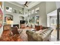 Inviting living room featuring a cozy fireplace, large windows, hardwood floors, and comfortable seating for relaxation at 2206 Eagles Nest Dr, Lafayette, CO 80026