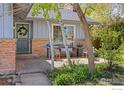Inviting front patio with cozy seating area, colorful rug, and view of lush greenery at 27 Cornell Dr, Longmont, CO 80503