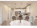 Well-lit kitchen and dining area featuring modern lighting, white cabinets and granite countertops at 2732 Bear Springs Cir, Longmont, CO 80503