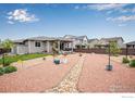 Spacious backyard with tasteful rock landscaping, grass, and a covered patio area at 3022 Merlin Dr, Brighton, CO 80601