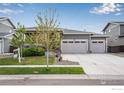 Inviting exterior featuring a two-car garage, gray siding, and manicured front lawn at 3022 Merlin Dr, Brighton, CO 80601