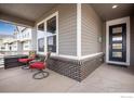 Cozy covered front porch with stylish chairs and a modern front door at 3022 Merlin Dr, Brighton, CO 80601