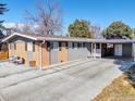 Single-story home featuring brick accents, a carport, blue door, and a well-maintained front yard at 4965 Ricara Dr, Boulder, CO 80303