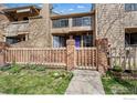 Attractive townhome featuring a gated brick fence, well-maintained lawn, and colorful front door at 5086 Buckingham Rd, Boulder, CO 80301