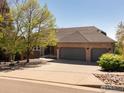 Brick home with large driveway and 3-car garage nestled within a tranquil landscape with mature trees and lush greenery at 6668 Fairways Dr, Longmont, CO 80503