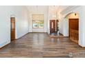Bright living room boasts vaulted ceilings, pristine white walls, and elegant laminate wood flooring with large front windows at 6668 Fairways Dr, Longmont, CO 80503