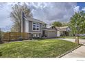 Exterior view of a well-maintained two-story home with a lush green lawn and mature trees at 709 Buchanan Ln, Longmont, CO 80504