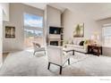 Open living area with vaulted ceilings, fireplace, modern furniture, and sliding glass doors to the outside at 87 Macon Ct, Aurora, CO 80010