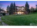 Backyard view showcasing a spacious lawn, mature trees, and a tiered deck perfect for entertaining at 9980 Newton Ct, Westminster, CO 80031