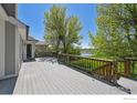 Spacious back deck with wood railing offering serene views of the lush green lawn and pond at 1105 Oakhurst Dr, Broomfield, CO 80020