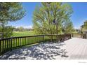 Large wooden deck with scenic views of mature trees and a grassy landscape at 1105 Oakhurst Dr, Broomfield, CO 80020