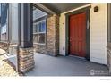 Inviting front porch with stone pillars and a red front door, enhancing curb appeal at 157 Ambrose St, Erie, CO 80516
