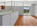 Open-concept living room with hardwood floors, geometric wall accent, and backyard view at 1573 S Dexter Way, Denver, CO 80222