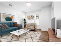 Bright living room features a blue sofa, neutral accent chair, white coffee table and wood floors at 1707 Walnut St # 102, Boulder, CO 80302