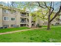 Tan condo building with lush green lawn, concrete sidewalks and a staircase to upper units at 20 S Boulder Cir # 2312, Boulder, CO 80303