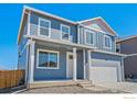 Charming two-story home featuring a two-car garage, covered porch, and a modern blue exterior at 2212 Crosswind St, Fort Lupton, CO 80621
