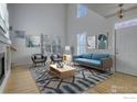 Bright living room with vaulted ceilings, a fireplace, neutral walls, hardwood floors, and a blue accent sofa at 3002 Shoshone Trl, Lafayette, CO 80026