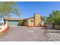 Side exterior view of the brick home featuring an attached garage, chimney, and steps to the elevated entryway at 3117 County Road 14 1/2, Erie, CO 80516