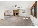 Spacious living room featuring plush carpeting, a brick fireplace, natural light, and neutral paint at 3117 County Road 14 1/2, Erie, CO 80516