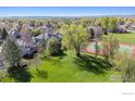 Aerial view of a backyard, tennis court, and mature trees in a lush green neighborhood at 4059 Nevis St, Boulder, CO 80301