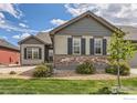 Stunning exterior of a home with stone accents, lush green lawn, and a tree in the yard at 4419 Maxwell Ave, Longmont, CO 80503