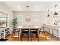 Bright dining area with wood table and chairs, adjacent to an open kitchen, featuring hardwood flooring at 4511 Bryant St, Denver, CO 80211