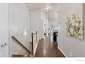 Hallway with hardwood floors leads to kitchen and living area with white paint and modern decor at 9137 Harlequin Cir, Longmont, CO 80504