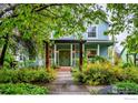 A beautiful house with blue siding, a pergola, and a green door surrounded by lush landscaping at 1369 Padfield Pl, Erie, CO 80516