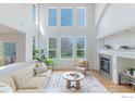 Sun-filled living room featuring soaring windows, a fireplace, and hardwood floors at 1414 Hoffman Dr, Erie, CO 80516