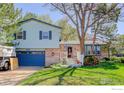 Charming home featuring a brick facade, blue siding, well-maintained lawn, mature trees, and a two-car garage at 470 Ash St, Broomfield, CO 80020