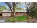 A well-maintained single-story home with brick facade, mature trees, and a green lawn at 6432 Owens St, Arvada, CO 80004