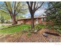 Inviting single-story brick home featuring mature trees and lush green lawn at 6432 Owens St, Arvada, CO 80004
