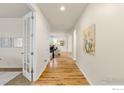 Hallway featuring hardwood floors and white walls, leading to rooms with inviting natural light at 687 Jarvis Dr, Erie, CO 80516