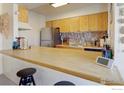 Kitchen boasts ample counter space, natural wood cabinets and stainless steel refrigerator at 8479 Everett Way # E, Arvada, CO 80005