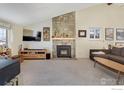 Cozy living room with a stone fireplace, plush carpeting, and comfortable seating at 8479 Everett Way # E, Arvada, CO 80005