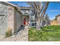 Charming home featuring a red front door and lush landscaping under a mature shade tree at 9125 W 95Th Ave, Westminster, CO 80021