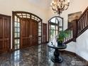 Grand foyer features marble floors, a striking chandelier, and a wood staircase with views of the exterior at 1189 Rembrandt Rd, Boulder, CO 80302