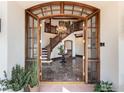 Elegant foyer showcasing a marble floor, wood staircase, and a stunning chandelier viewed through an arched wood doorway at 1189 Rembrandt Rd, Boulder, CO 80302