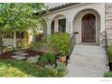 A carved wood front door is accented by the arched entrance, stone and well maintained landscaping at 1376 S Clayton St, Denver, CO 80210