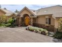Inviting entrance with a stone archway and wood door, framed by lush landscaping and flowering plants at 1426 Rembrandt Rd, Boulder, CO 80302