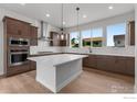 Bright kitchen featuring an island, stainless steel appliances, and stylish brown cabinets at 14283 Currant St, Broomfield, CO 80020