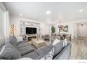 Bright and open living room with a large gray sectional, fireplace, TV, dining area, and wood-look flooring at 14762 Charbray St, Mead, CO 80542
