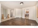 Open living area showcasing hardwood floors with staircase, kitchen, and hallway access at 2072 Skylark Ct, Longmont, CO 80503