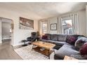 Bright living room featuring a plush gray sectional sofa, wood floors, and a rustic coffee table at 4009 W 52Nd Ave, Denver, CO 80212