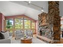 Spacious living room featuring a stone fireplace, vaulted ceilings, and large windows with scenic views at 560 Northstar Ct, Boulder, CO 80304